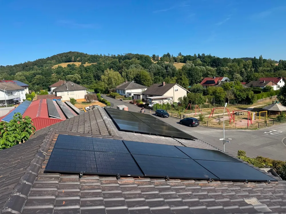 Modulfeld auf einem Ziegeldach vor Dorf- und Hügelkulisse im Landkreis Hersfeld-Rotenburg