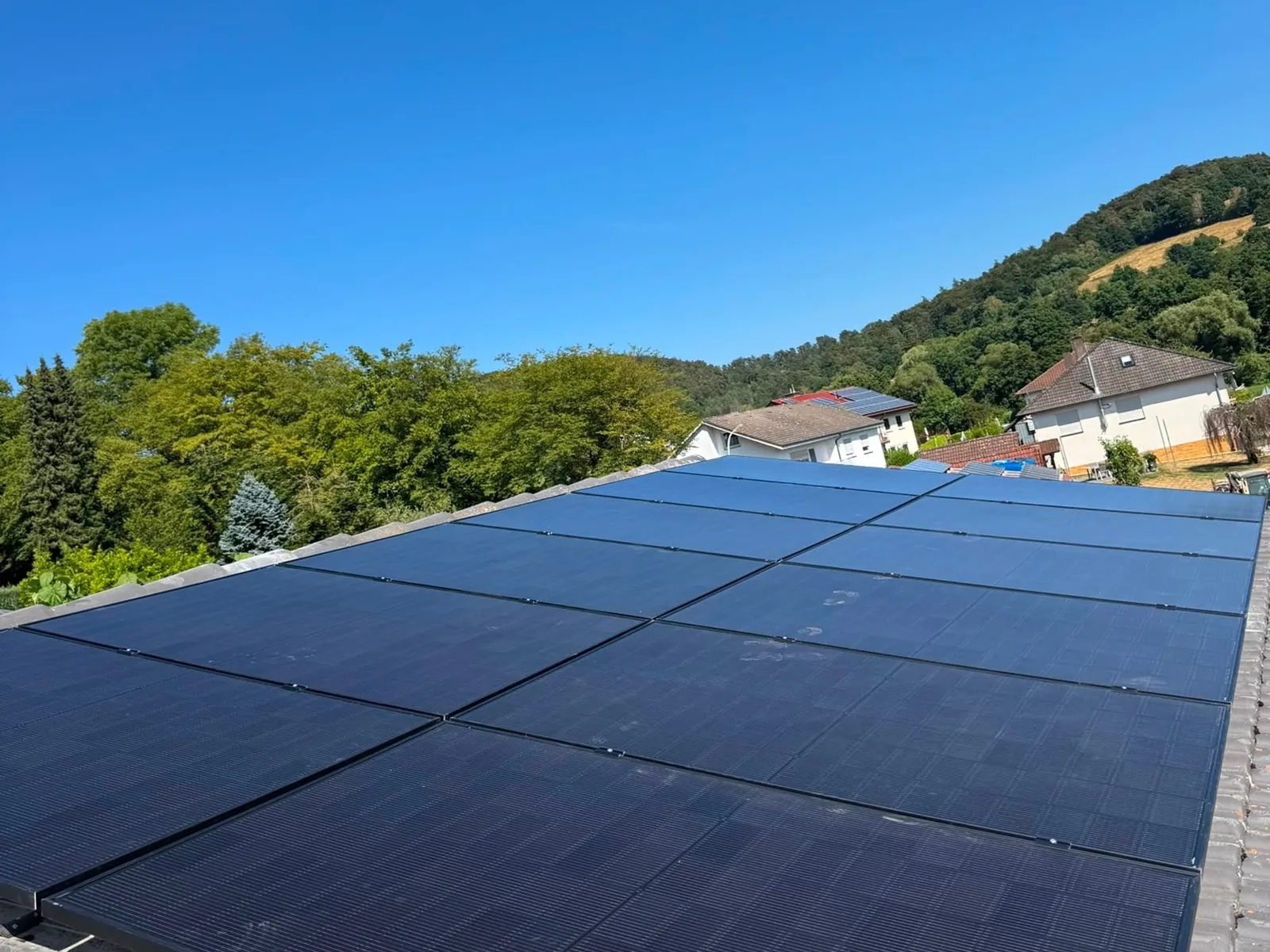 Photovoltaikanlage auf einem Ziegeldach vor bewaldeter Hügelkulisse im Landkreis Hersfeld-Rotenburg