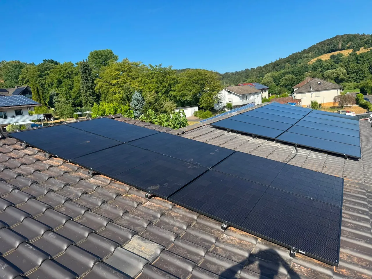 Photovoltaikanlage auf einem Ziegeldach mit Blick über ein Dorf und die Hügel im Landkreis Hersfeld-Rotenburg